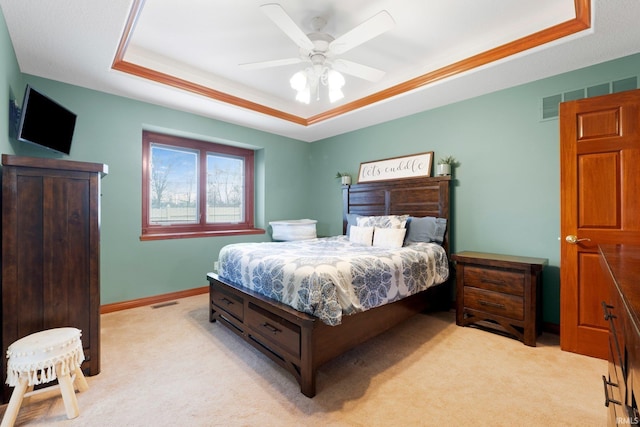 bedroom featuring a tray ceiling, light carpet, a ceiling fan, and baseboards