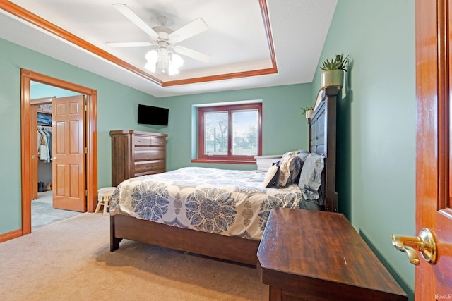 carpeted bedroom with a raised ceiling and a ceiling fan