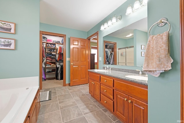 bathroom featuring double vanity, a shower stall, a spacious closet, and a garden tub