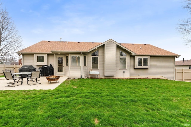 rear view of property featuring a fire pit, a patio area, and a shingled roof