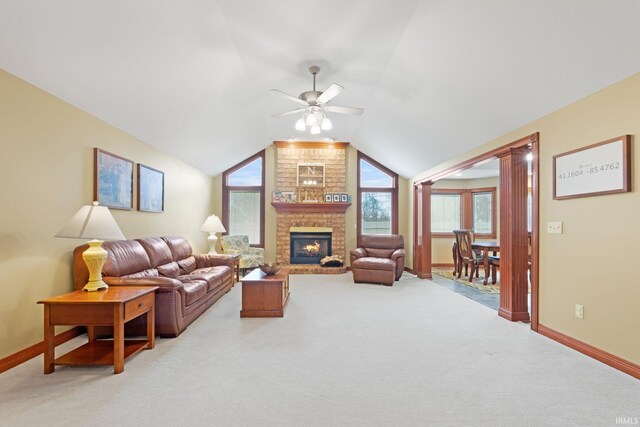 living area featuring light colored carpet, baseboards, ceiling fan, lofted ceiling, and a fireplace