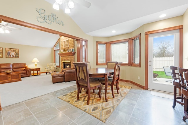 dining room featuring a ceiling fan, lofted ceiling, a fireplace, baseboards, and recessed lighting