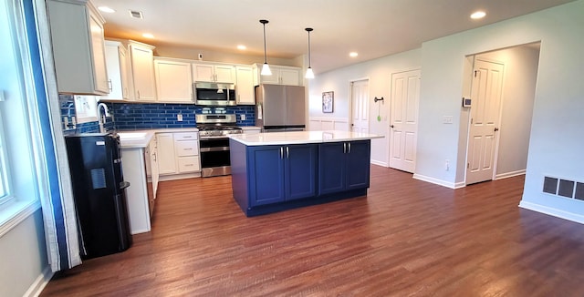 kitchen with appliances with stainless steel finishes, a kitchen island, a sink, dark wood-style flooring, and light countertops