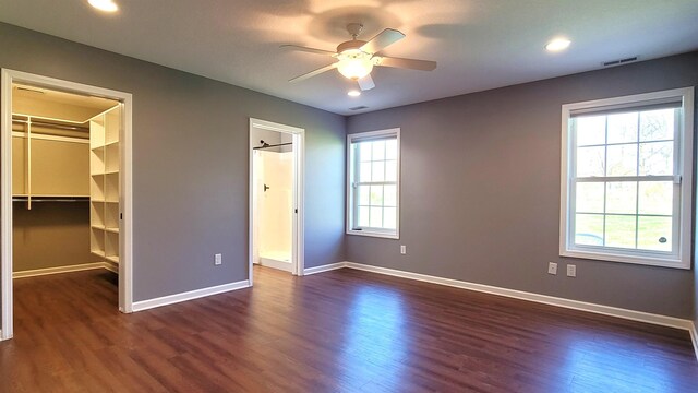 unfurnished bedroom with dark wood-style flooring, a spacious closet, baseboards, and recessed lighting