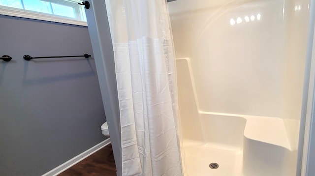 full bath with a stall shower, toilet, and baseboards