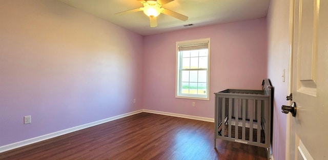 empty room featuring dark wood finished floors, baseboards, and a ceiling fan