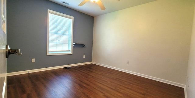 empty room featuring healthy amount of natural light, a ceiling fan, and dark wood finished floors