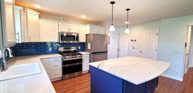 kitchen featuring stainless steel appliances, wood finished floors, a sink, decorative backsplash, and recessed lighting