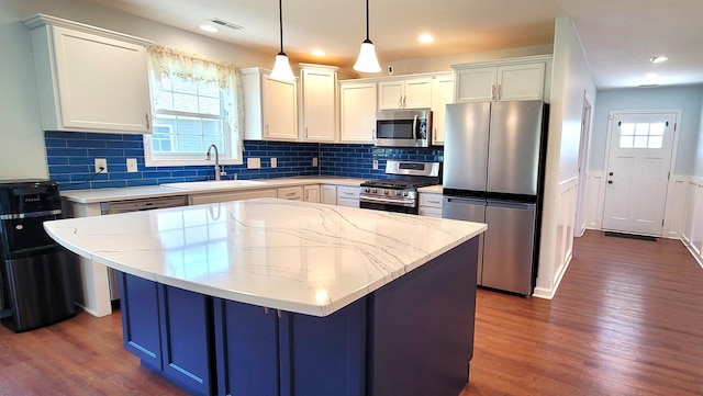 kitchen with appliances with stainless steel finishes, a sink, dark wood finished floors, white cabinetry, and recessed lighting