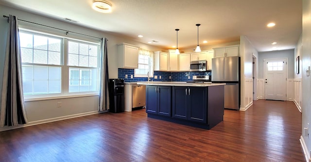 kitchen with stainless steel appliances, dark wood finished floors, a kitchen island, decorative backsplash, and white cabinets
