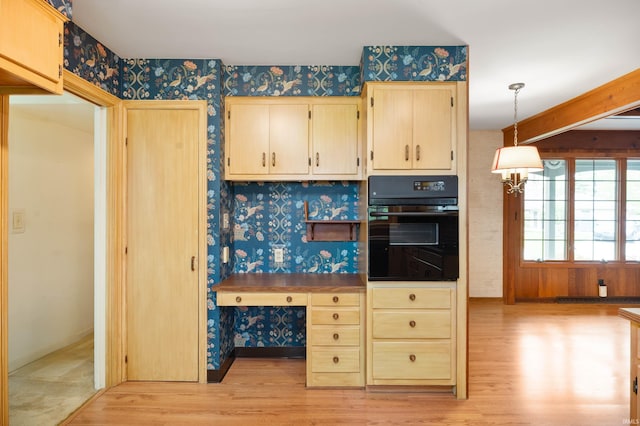 kitchen featuring oven, wallpapered walls, light wood-style floors, pendant lighting, and light brown cabinetry