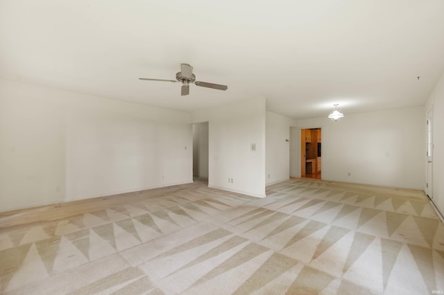 empty room featuring light carpet, a ceiling fan, and baseboards