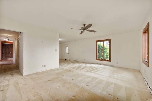 unfurnished room with a baseboard radiator, plenty of natural light, and light colored carpet