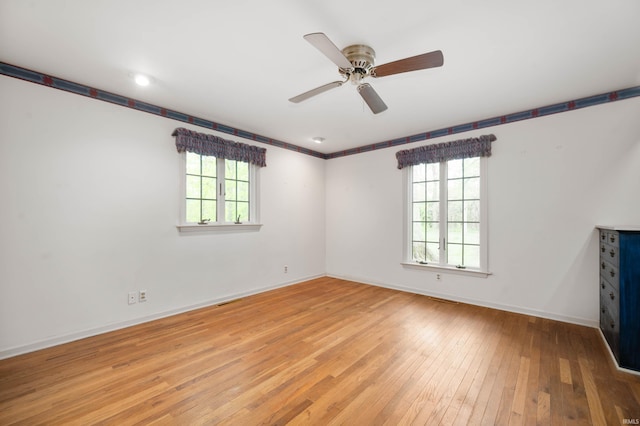 spare room featuring healthy amount of natural light, light wood-style flooring, ceiling fan, and baseboards