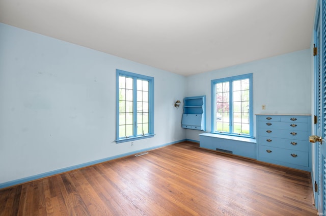 spare room with wood finished floors, plenty of natural light, and baseboards