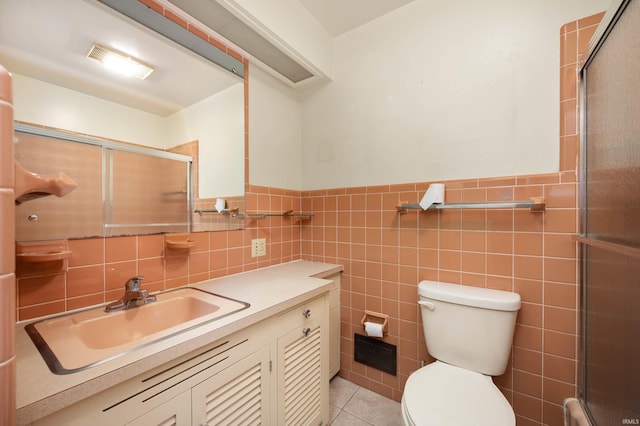 bathroom featuring a stall shower, toilet, a wainscoted wall, vanity, and tile walls