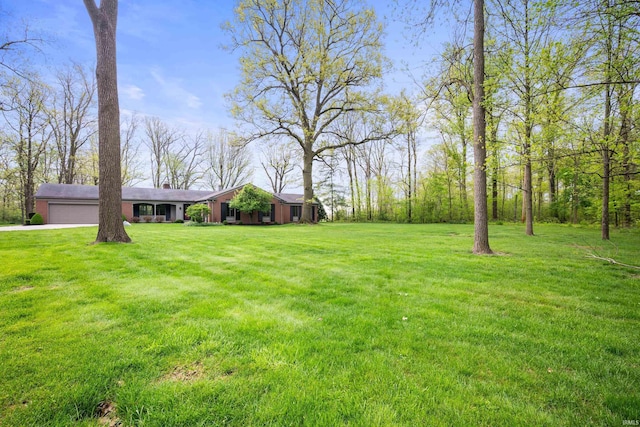 view of green lawn with a garage and driveway