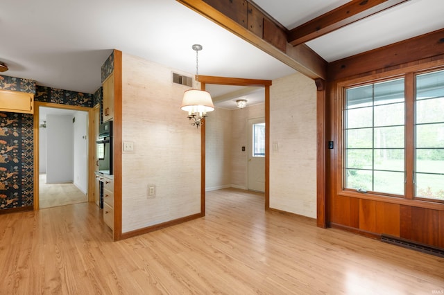unfurnished dining area featuring light wood-style floors, a chandelier, beamed ceiling, baseboards, and wallpapered walls