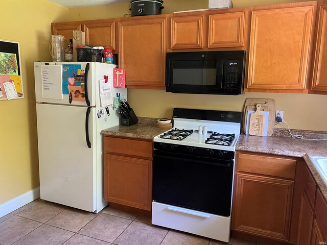 2800 E Bernice Dr, Bloomington, IN 47401 - kitchen with black microwave, freestanding refrigerator, gas range, and light tile patterned floors