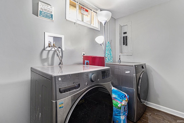 washroom with washing machine and dryer, baseboards, wood finished floors, and electric panel