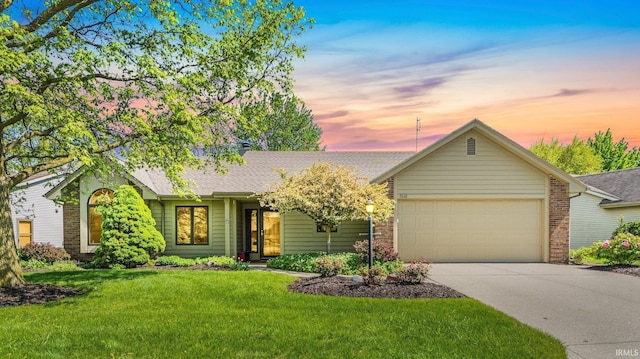 ranch-style home with a garage, a yard, driveway, and roof with shingles