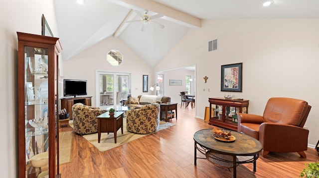 living area featuring light wood-type flooring, a ceiling fan, beamed ceiling, high vaulted ceiling, and baseboards