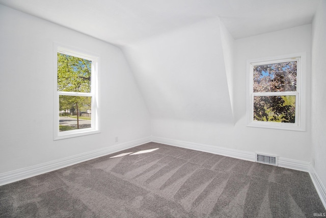 carpeted empty room featuring vaulted ceiling and baseboards