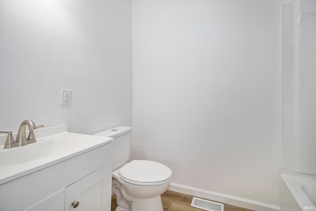 bathroom with toilet, vanity, baseboards, a tub, and wood finished floors