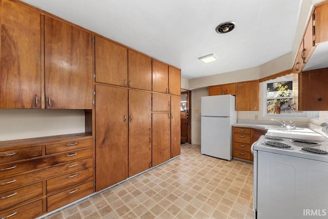 221 S Ironwood Dr, South Bend, IN 46615 - kitchen with white appliances, light flooring, brown cabinets, and a sink