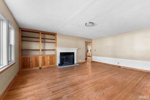 221 S Ironwood Dr, South Bend, IN 46615 - unfurnished living room featuring light wood finished floors, a fireplace with raised hearth, and baseboards