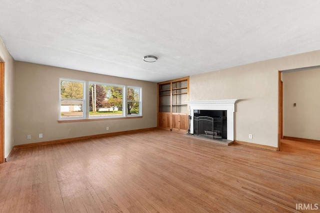 221 S Ironwood Dr, South Bend, IN 46615 - unfurnished living room featuring light wood-type flooring, a fireplace with raised hearth, built in features, and baseboards