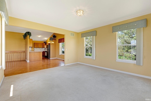 8928 Goshawk Ln, Fort Wayne, IN 46825 - unfurnished living room featuring light carpet, baseboards, and light wood finished floors