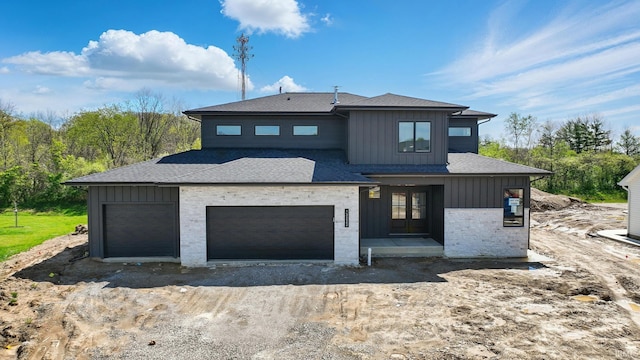 13222 Malfini Trl, Fort Wayne, IN 46845 - view of front of property featuring board and batten siding, dirt driveway, roof with shingles, and a garage