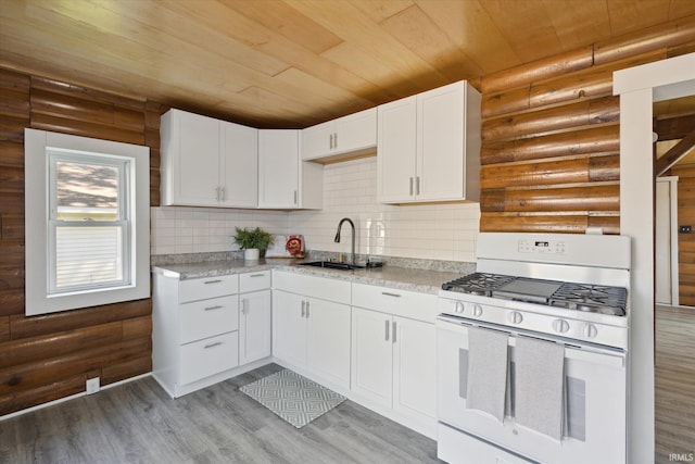 kitchen featuring gas range gas stove, log walls, wooden ceiling, a sink, and white cabinetry