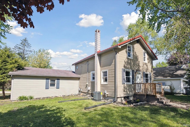 rear view of house featuring central AC, a chimney, and a yard