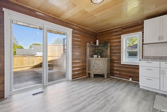 entryway featuring wooden ceiling, rustic walls, and light wood-type flooring