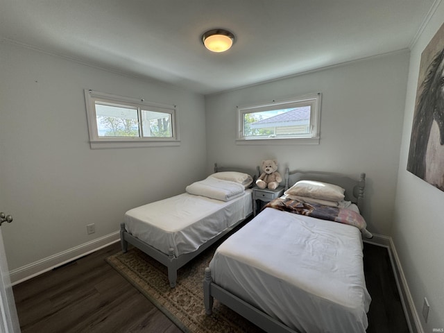 bedroom featuring multiple windows, dark wood-style flooring, baseboards, and crown molding