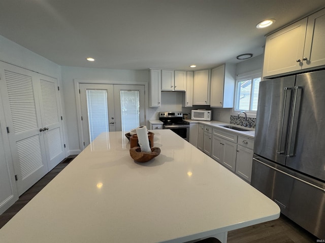 kitchen with appliances with stainless steel finishes, a sink, french doors, a kitchen island, and light countertops