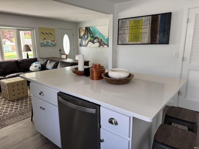 kitchen featuring stainless steel dishwasher, open floor plan, light countertops, and white cabinets