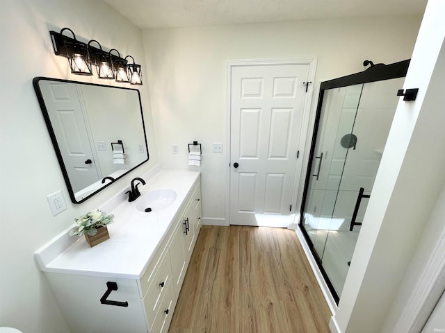 bathroom featuring wood finished floors, a stall shower, and vanity