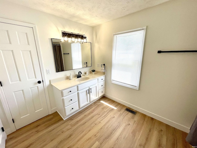 bathroom featuring wood finished floors, a textured ceiling, baseboards, and vanity