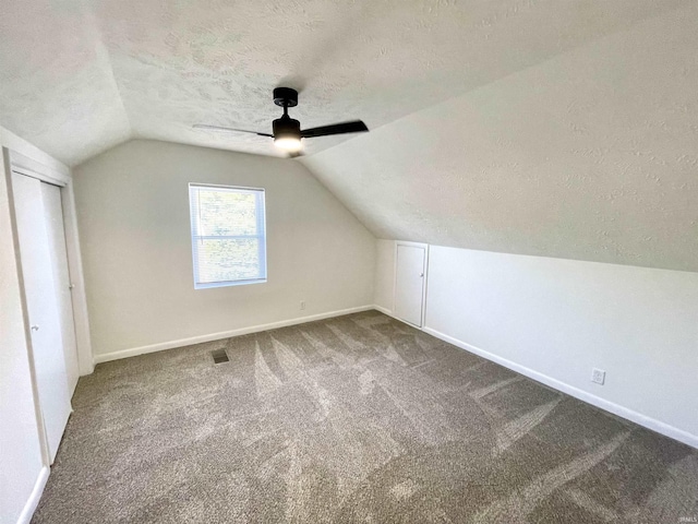 bonus room with a textured ceiling, ceiling fan, lofted ceiling, baseboards, and carpet