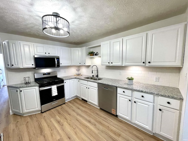 kitchen with stainless steel appliances, a sink, a textured ceiling, open shelves, and white cabinetry