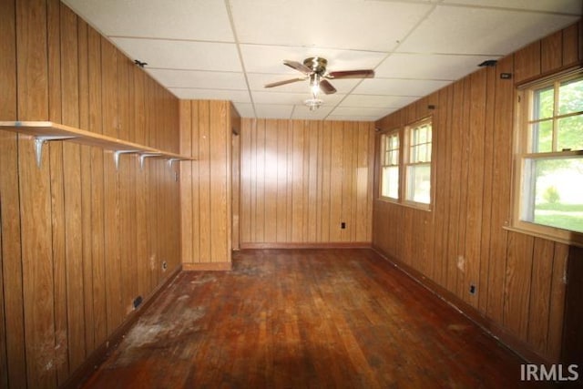 128 E Washington St, Williamsport, IN 47993 - empty room featuring dark wood finished floors, ceiling fan, wood walls, baseboards, and a paneled ceiling