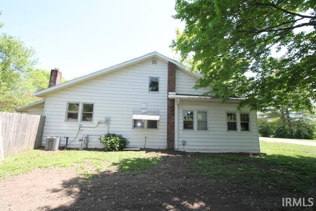 128 E Washington St, Williamsport, IN 47993 - rear view of property with central air condition unit, fence, and a chimney
