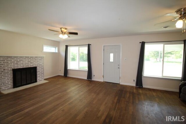 128 E Washington St, Williamsport, IN 47993 - unfurnished living room featuring ceiling fan, wood finished floors, baseboards, and a brick fireplace