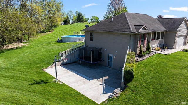 706 Taylor Ln, Albion, IN 46701 - rear view of house with a trampoline, a lawn, an outdoor pool, an attached garage, and roof with shingles