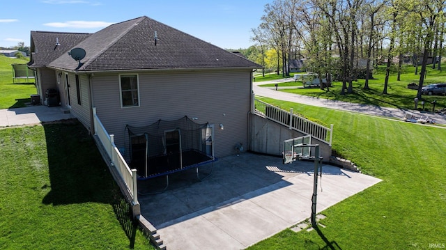 706 Taylor Ln, Albion, IN 46701 - back of house with a shingled roof, a trampoline, and a lawn
