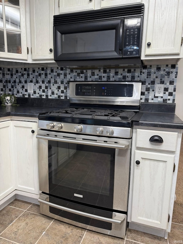 kitchen with stainless steel gas stove, black microwave, backsplash, and dark countertops