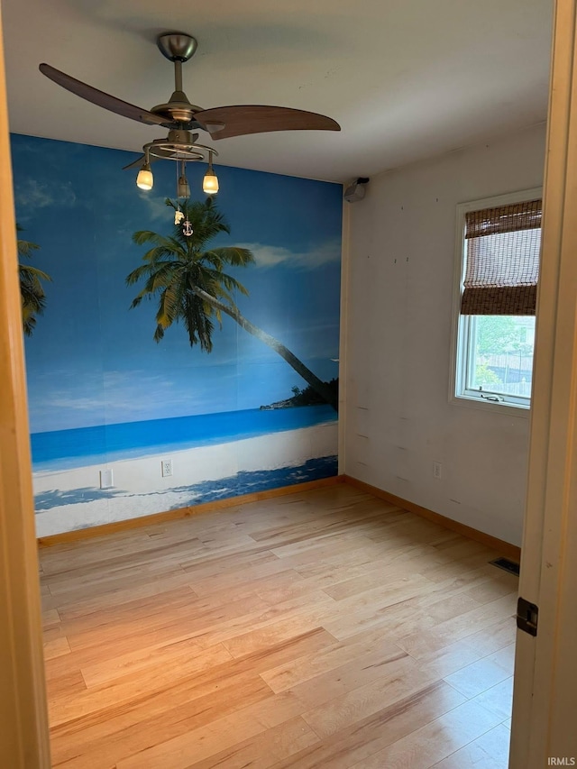 unfurnished room with wood finished floors, a ceiling fan, and baseboards